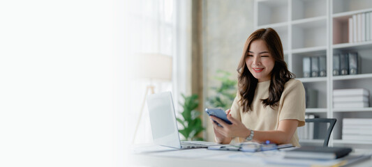 Portrait of beautiful young businesswoman standing smiling and using smartphone
