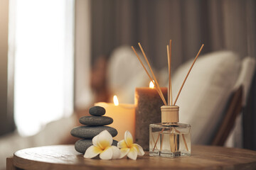 Spa, aromatherapy and candles on table for zen, calm and peace to relax for health and wellness. Stones, flowers and diffuser for self care, holistic massage and hospitality at a beauty salon - obrazy, fototapety, plakaty