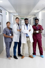 Unaltered portrait of diverse group of serious doctors with arms crossed in hospital, copy space
