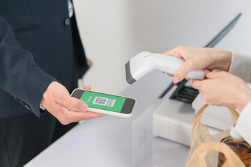 コンビニ・スーパーでQRコード決済するビジネスマン
