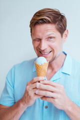 Close-up portrait of middle-aged man in blue shirt eating cone lavender ice cream.