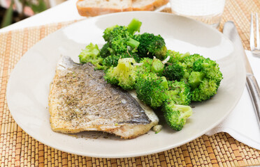 dish of fried dorado fish fillet with boiled broccoli