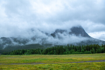 Misty majestic mountains with green meadows and an unpaved path in Banff Canada