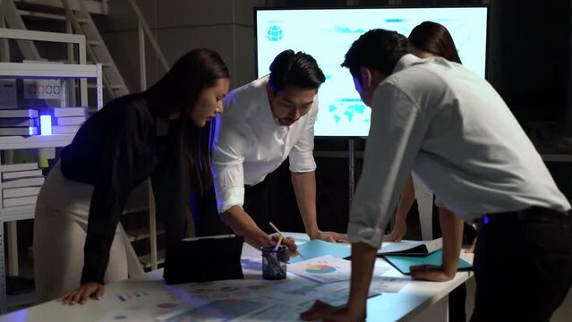 Young business people in workplace discussing and business planning with brainstorming meeting in office to night. Businessman and businesswoman planning and trading with negotiate partnership.