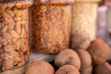 Various beans and nuts in glass jars on shelves of market in Goa. Legumes and dried coconut kernels sold at commerce.