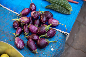 Quantity of purple small eggplants piled up on tablecloth in market in Goa. Healthy brinjals sold...