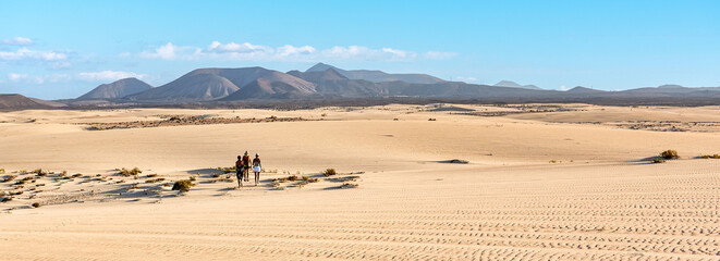 Fototapeta na wymiar Traveler friends on a hike the sand dunes of a deserted landscape - Adventure travel concept