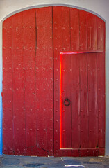 Old shabby ajar wooden door in the wall of the house