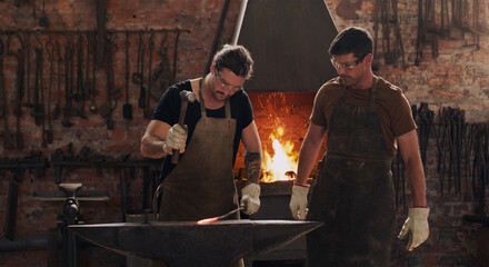 Hammer, anvil and fire with men working in a forge for metal work manufacturing or production....