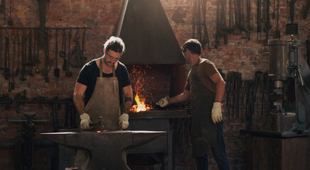 Hammer, anvil and fire with men working in a foundry for metal work manufacturing or production....