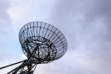 Bottom view of a radio satellite against a blue cloudy sky