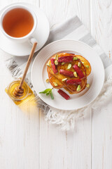 Vanilla Roasted Rhubarb French Toast with pistachios and honey close-up on a plate on a wooden table. Vertical top view from above