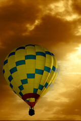 Hot air balloon in flight in an early morning cloudy sky, with sunlight shining on balloon.