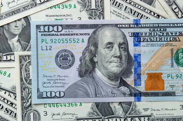 A close-up shot showcasing a magnified half view of President Franklin on a 100 USD banknote, amidst a background of scattered 1 USD bills.