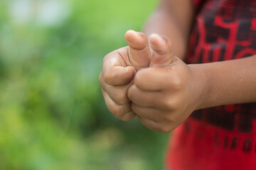 The two hands are in fists and the background is a green blur