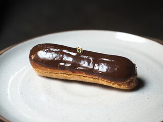 eclair with shiny chocolate glaze and gold leaf