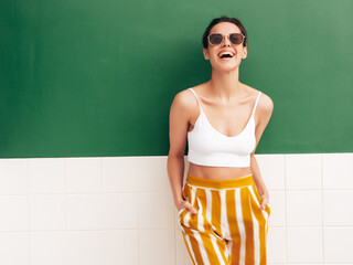Fashion young beautiful smiling female in trendy summer white top t-shirt and yellow striped pants....