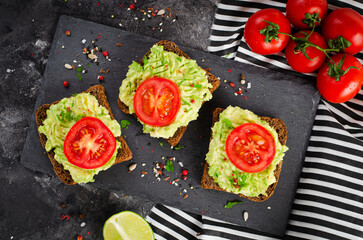 Avocado Toasts with Tomato, Healthy Snack or Breakfast on Dark Background