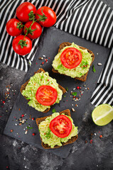 Avocado Toasts with Tomato, Healthy Snack or Breakfast on Dark Background