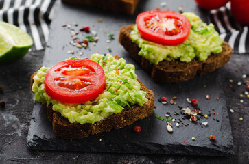 Avocado Toasts with Tomato, Healthy Snack or Breakfast on Dark Background