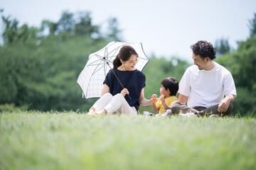 Asian family relaxing on park lawn with mother under parasol Relaxing on leisure seat Copy space...