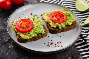 Avocado Toasts with Tomato, Healthy Snack or Breakfast on Dark Background
