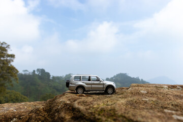 Concept for traveling and adventure. A toy car placed on a giant rock, after some edits.