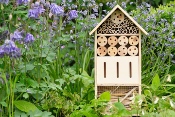 An insect hotel or bee hotel in a summer garden. An insect hotel is a manmade structure created to provide shelter for insects in a variety of shapes and sizes and materials.	