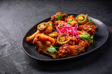 Grilled Lemon and garlic chicken wings with pickled root vegetables and jalapenos. Asia style cuisine.