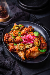 Grilled Lemon and garlic chicken wings with pickled root vegetables and jalapenos. Asia style cuisine.