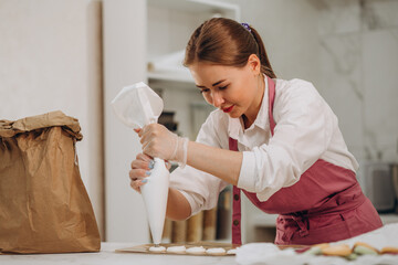 cooking, food and baking concept - chef with confectionery bag squeezing cream filling to macarons...