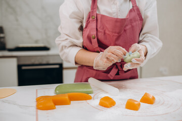 Woman shaping piece of mochi sticky glutinous rice cake dusted with starch flour to make dessert