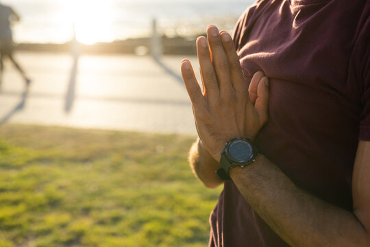 Midsection of biracial man doing yoga with hands in prayer pose, on promenade at sundown, copy space