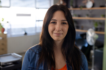Portrait of happy caucasian female customer with long dark hair smiling at hair salon