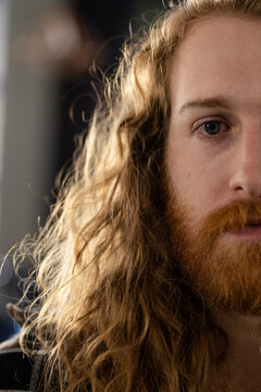 Half portrait of caucasian male customer with long curly red hair and beard at hair salon