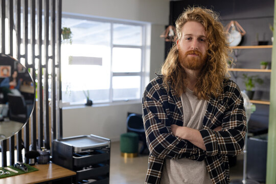 Portrait of happy caucasian male customer with long curly red hair and beard at hair salon