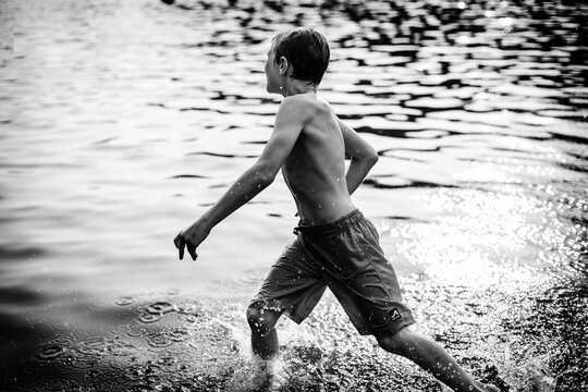 Boy splashing through lake during summer evening