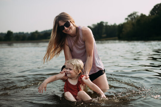 Mom playing with child in water during summer vacation