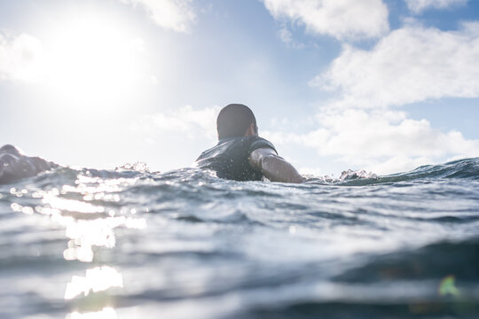 Portrait of surfer man paddling in sea against clear sky