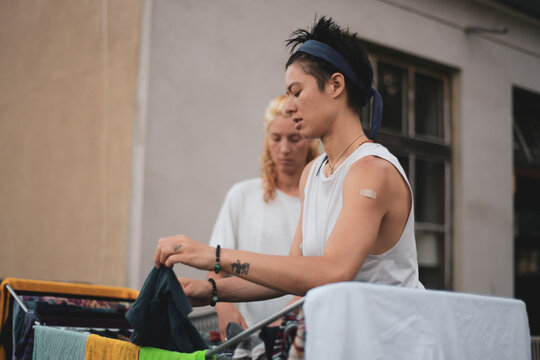 queer couple hang laundry on clothes rack outside on balcony