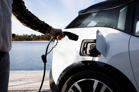 Person plugging in an electric car by the water in Stockholm