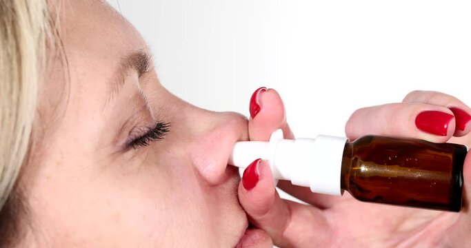 Woman dripping vasoconstrictor drops into nose in profile 4k movie. Treatment of acute respiratory infections and rhinitis concept