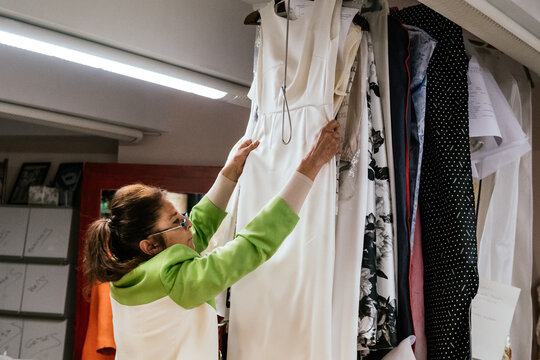 dressmaker placing dress on the hanger in her workshop