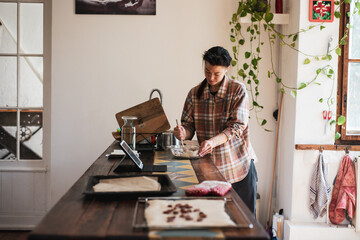 person baking at home with trays for oven mixes from online recipe