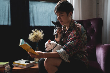 person reads to small dogs in vintage chair in window light