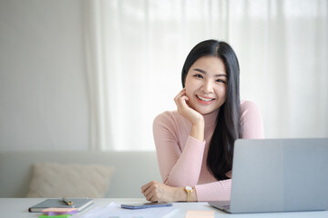 A beautiful Asian businesswoman sitting in her private office, she is checking company financial documents, she is a female executive of a startup company. Concept of financial management.