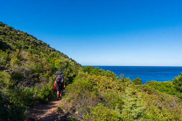 young woman tourist with backpack on background panoramic view from the mountains on the island of Sardinia in clear weather, Monte Corrasi, Italy