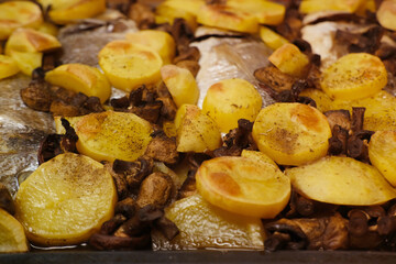 oven grilled sea bream fish with delicious curry sauce served on baking tray, baked potatoes with champignon mushrooms, spices, junk food concept, traditional family party, fish dishes
