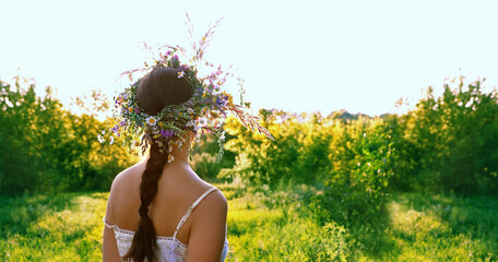 Girl in flower wreath on meadow, sunny green natural background. Floral crown, symbol of Midsummer, summer solstice. ritual ceremony for wiccan Litha sabbat. pagan holiday Ivan Kupala. banner - obrazy, fototapety, plakaty
