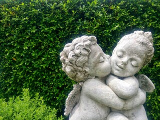 Fototapeta premium Cupid and Angel statue, Boy's statue kissing girl in garden.